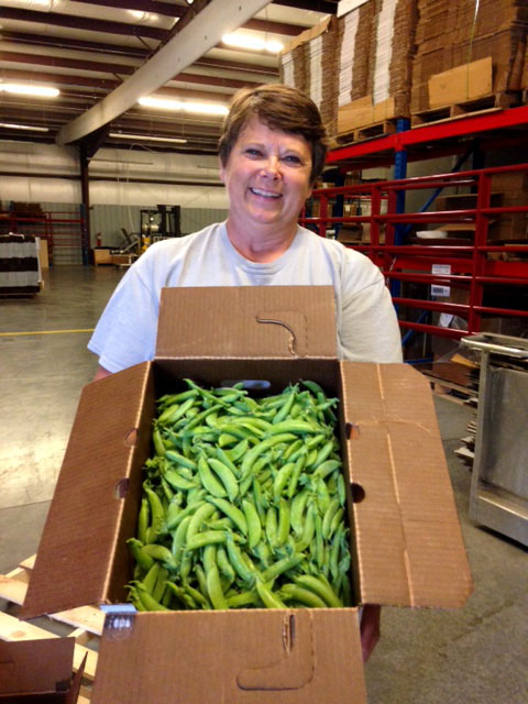 A woman holding a large box of sweet peas